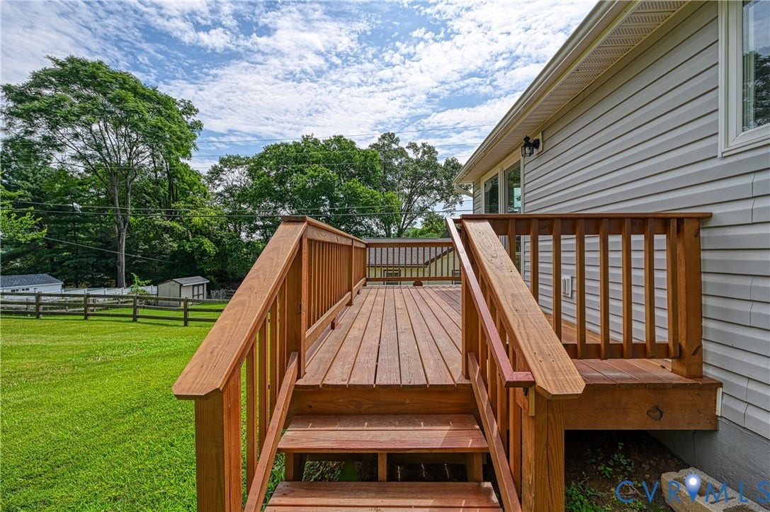 309 Ellis Drive, Louisa, VA 23093 Expansive wood deck with stairs and railing, providing outdoor access from the home's vinyl siding exterior