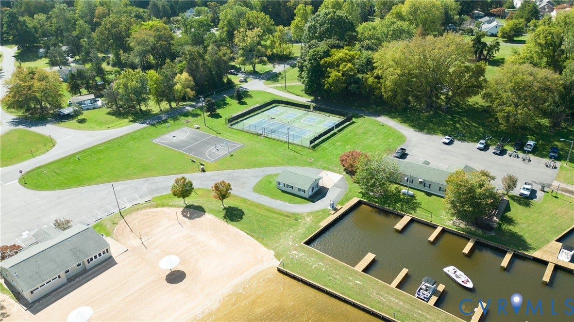 309 Ellis Drive, Louisa, VA 23093 Waterfront property featuring a private marina with multiple boat slips, an adjacent sandy beach area, a recreation building with a dark roof, tennis courts, and a basketball court