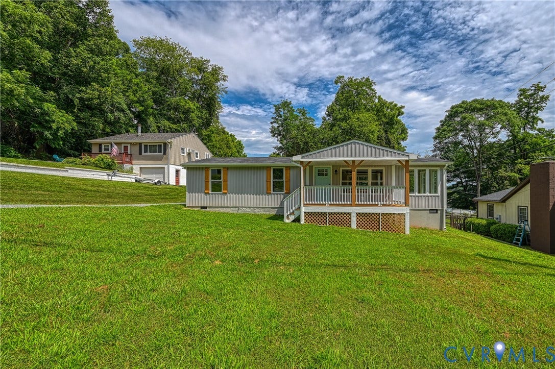 309 Ellis Drive, Louisa, VA 23093 Light gray siding home featuring a covered front porch with natural wood posts, white railing, and lattice skirting