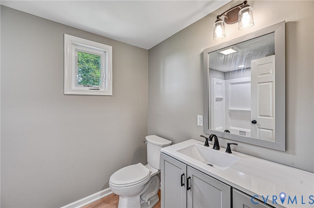 309 Ellis Drive, Louisa, VA 23093 Bathroom featuring a single window, a light gray vanity with a white countertop and integrated sink, matte black faucet fixtures, a framed mirror, and a two-bulb vanity light