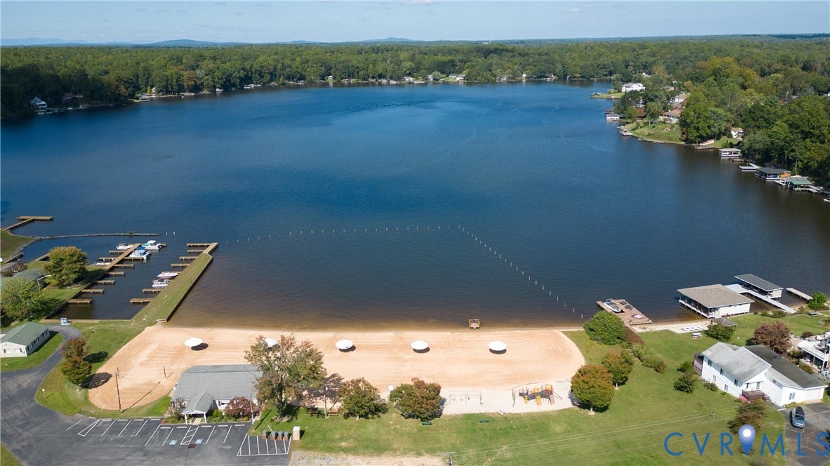 309 Ellis Drive, Louisa, VA 23093 Expansive lakefront property featuring a sandy beach, multiple boat docks, and a paved parking area