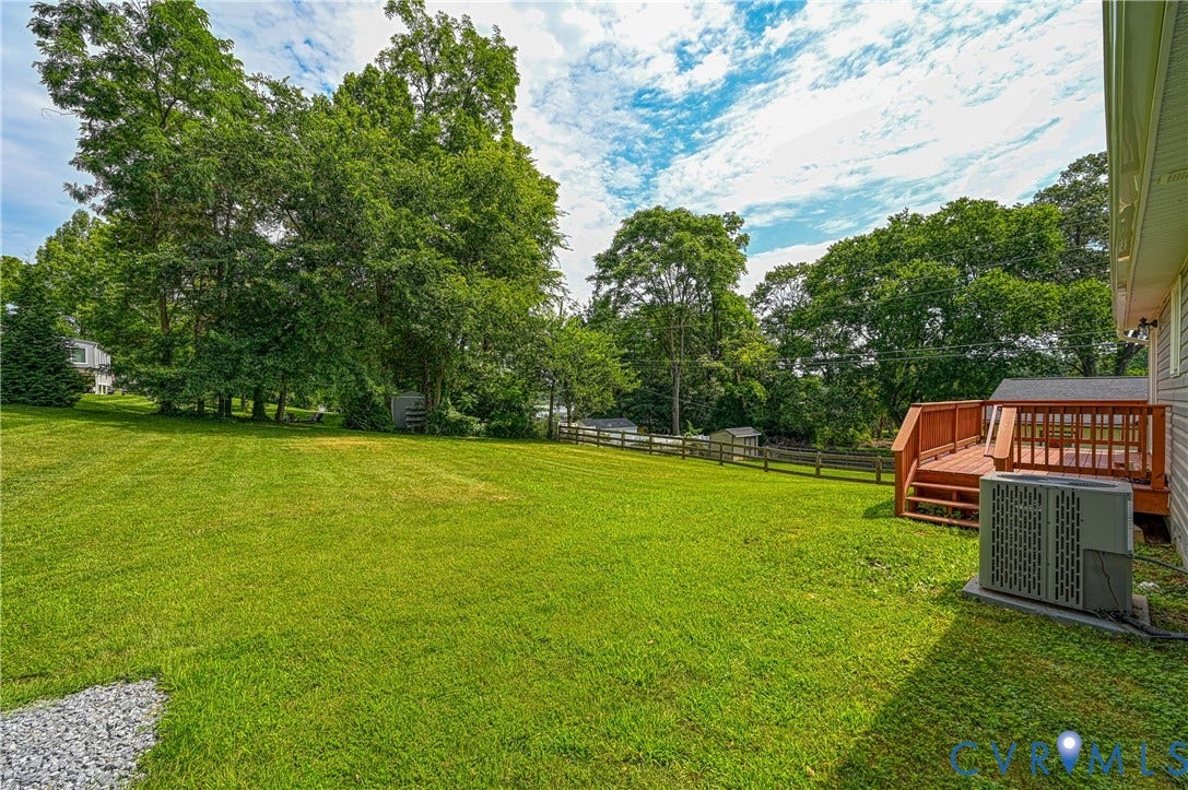 309 Ellis Drive, Louisa, VA 23093 Expansive backyard featuring a manicured lawn, mature trees, and a wooden deck with railing