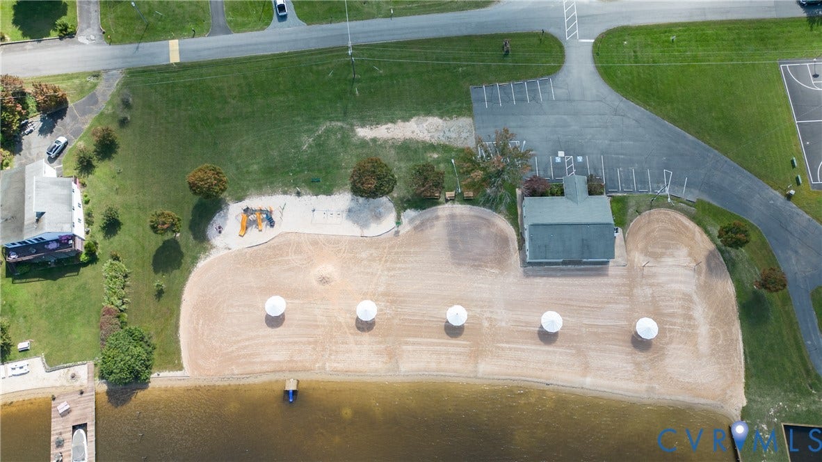 309 Ellis Drive, Louisa, VA 23093 Lakeside property featuring a sandy beach area, four fixed shade structures, and a dedicated building with a dark-pitched roof