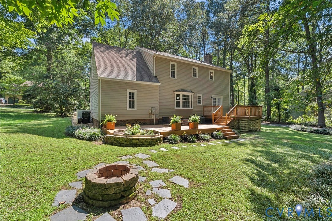 13908 Sterlings Bridge Road, Midlothian, VA 23112 Two-story exterior with light-colored siding, a multi-level wood deck, stone-lined fire pit, and a stone-lined garden bed