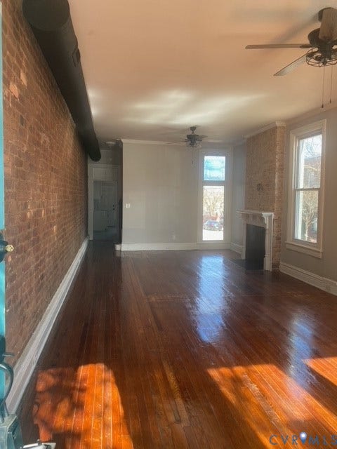 1100 W Marshall Street, Richmond, VA 23220 Spacious room featuring exposed brick walls, rich wood-finish flooring, and multiple windows