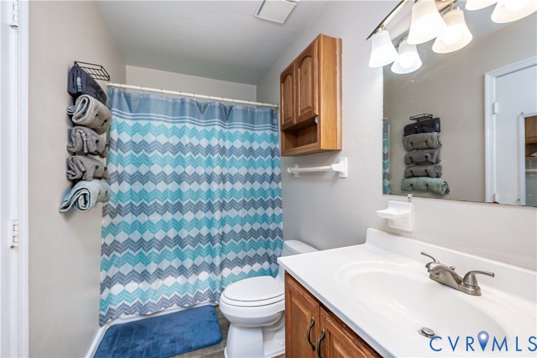 19105 Braebrook Drive, Chesterfield, VA 23834 Full bathroom featuring a white vanity with integrated sink, wood-finish cabinetry, brushed nickel faucet, and an overhead mirror with vanity lighting