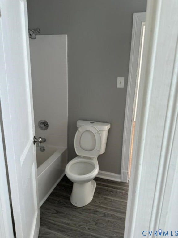 712 S Meadow Street, Richmond, VA 23220 Bathroom featuring a white toilet, white bathtub with chrome fixtures, and wood-finish flooring