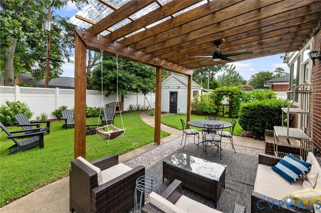 Expansive patio featuring a wood pergola with a clear roof, a ceiling fan, and a stone-finish surface