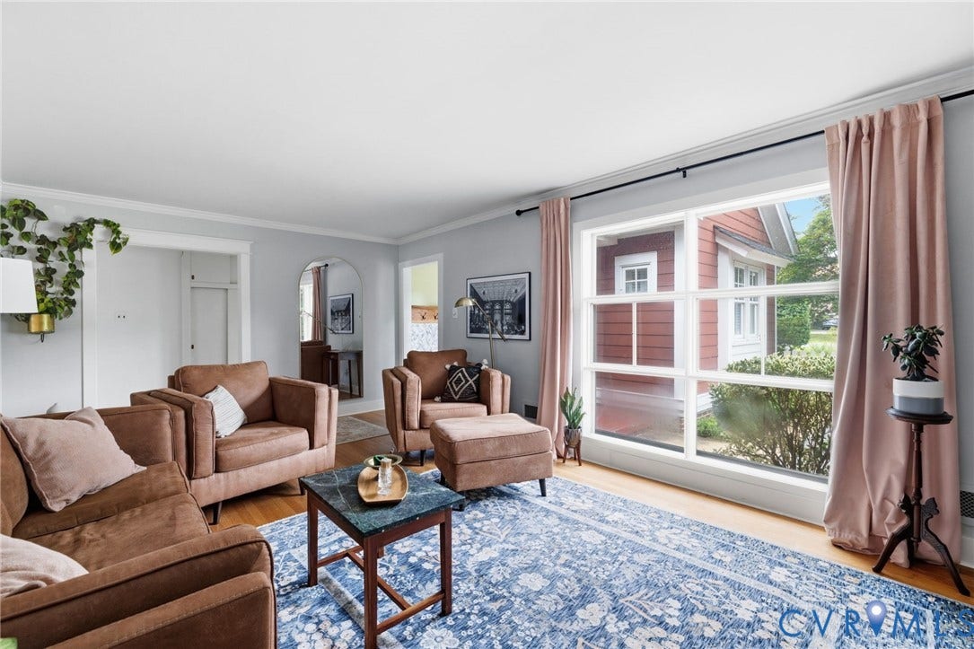 Bright living room featuring wood-finish flooring, a large multi-pane window, and light-toned wall paint