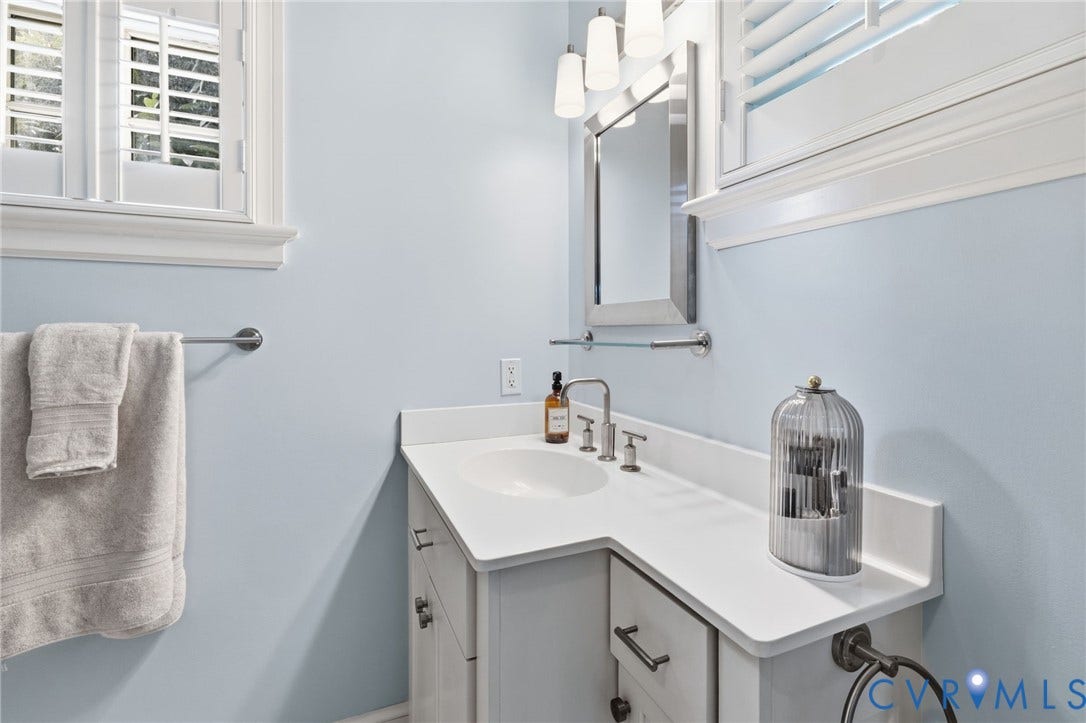 Bathroom featuring a white vanity with a built-in sink, brushed nickel faucet, and white countertop