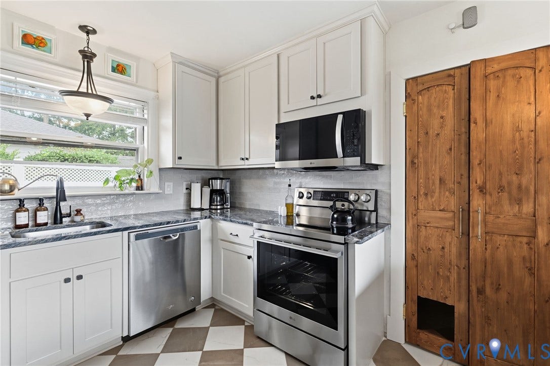 Kitchen featuring white shaker cabinetry, dark stone countertops, stainless steel appliances, a gray tile backsplash, and checkered floor tiles