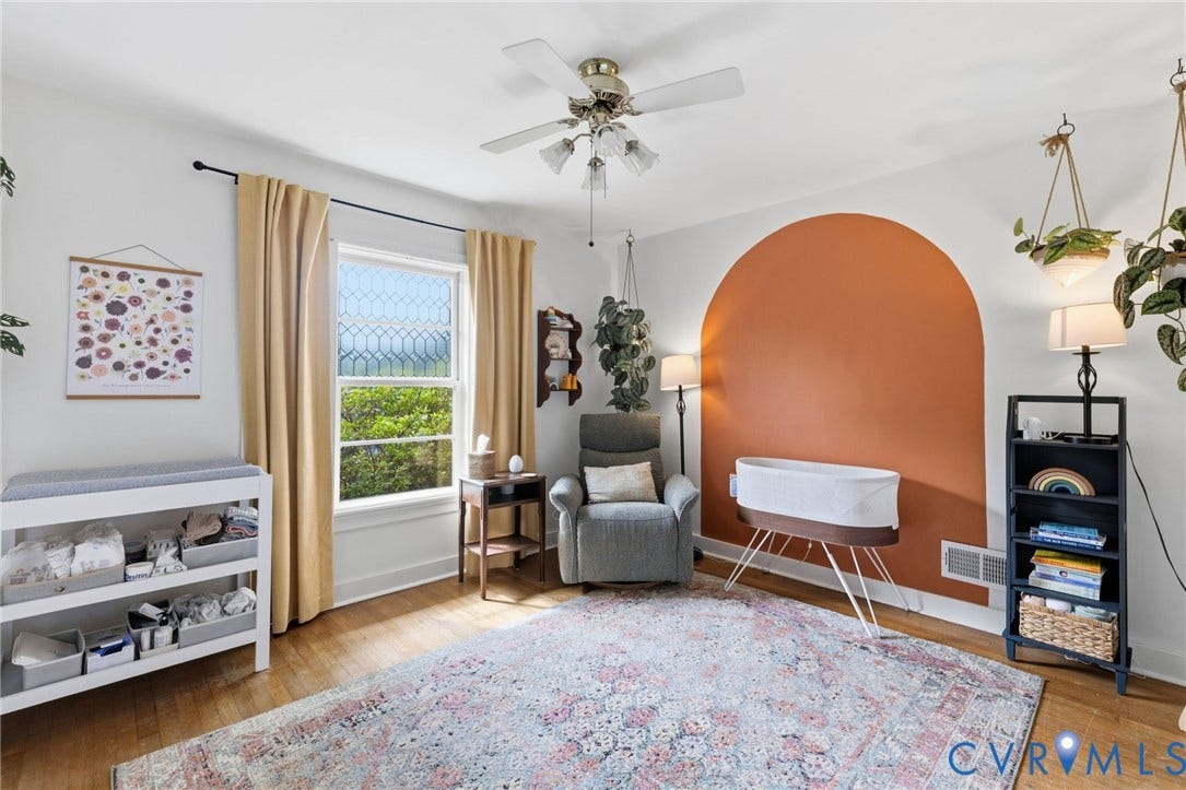 Spacious room featuring wood-finish flooring, a decorative arched wall detail, a ceiling fan with light fixture, and a window with a patterned privacy film