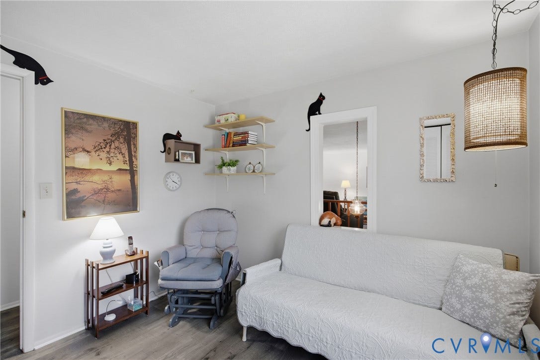 2007 Mountain Pine Boulevard, Three Pines, Richmond, VA 23235 Bright, light-filled bedroom featuring wood-finish flooring, a large upholstered sofa bed, floating shelves with display space, a glider chair, and a woven pendant light fixture