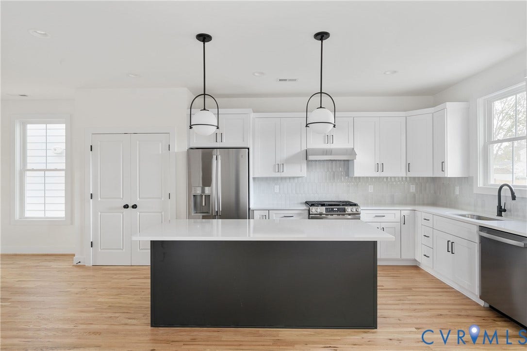 1103 Carlisle Avenue, Montrose Heights, Richmond, VA 23231 Modern kitchen featuring a dark-toned island with a light-toned countertop, white cabinetry with dark hardware, and stainless steel appliances including a refrigerator, range, and dishwasher