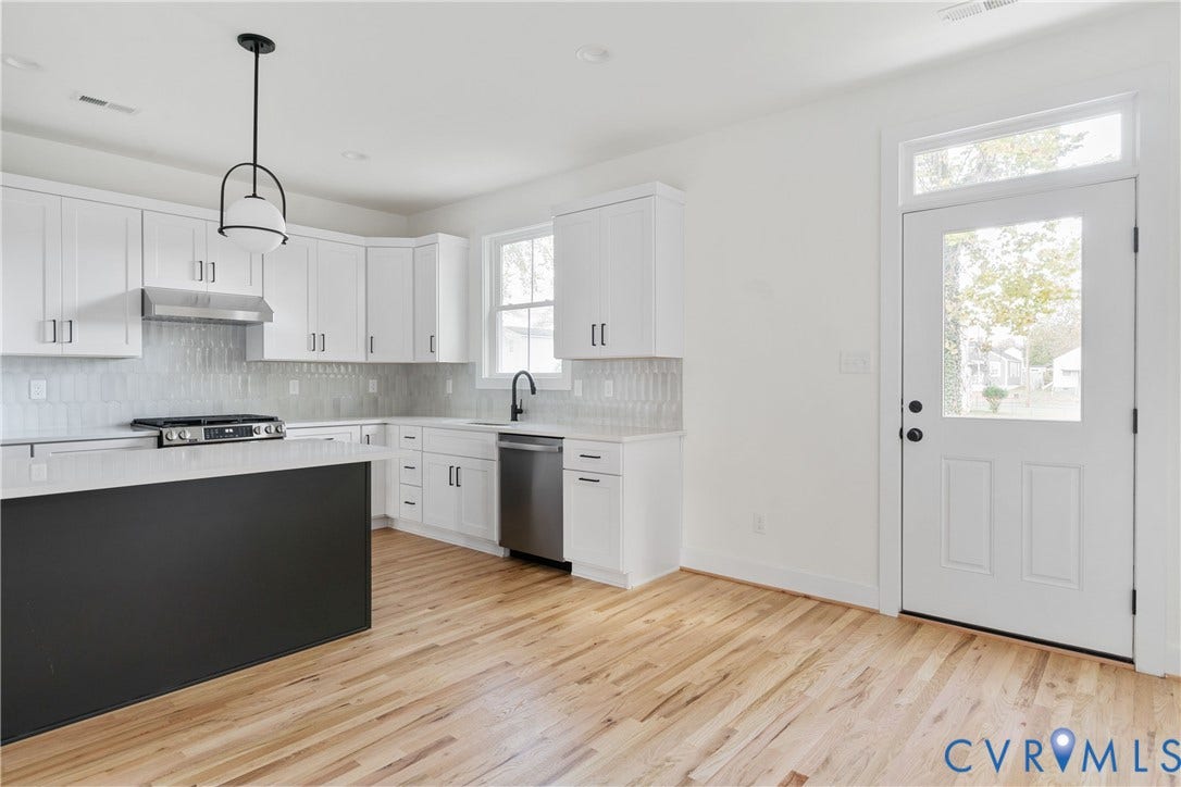 1103 Carlisle Avenue, Montrose Heights, Richmond, VA 23231 Kitchen featuring light wood-finish flooring, white cabinetry, stainless steel appliances, a black island, and a glass-paneled door with transom window
