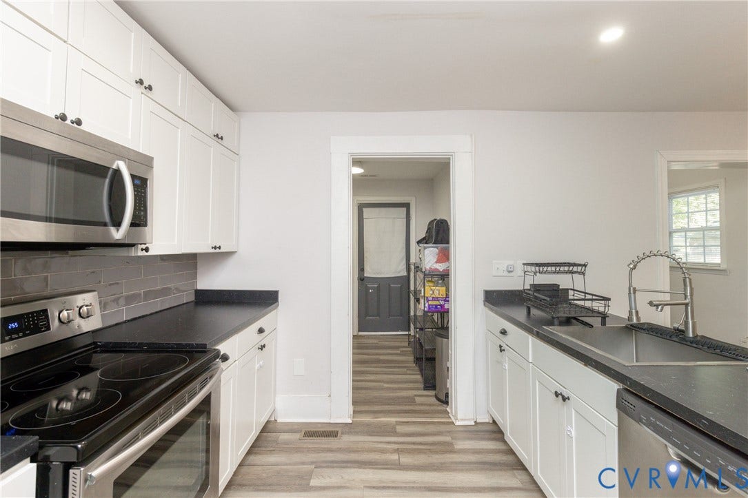 716 E Gladstone Avenue, Richmond, VA 23222 White shaker-style cabinetry, stainless steel appliances, dark countertops, a subway tile backsplash, and wood-finish flooring