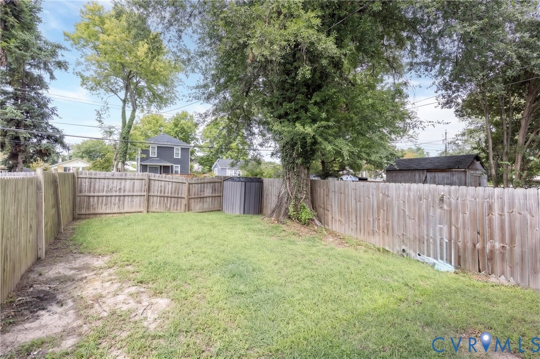 716 E Gladstone Avenue, Richmond, VA 23222 Fully fenced backyard featuring a mature tree, grassy area, and storage shed