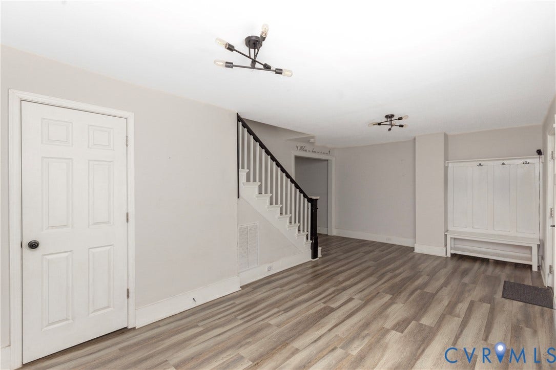 716 E Gladstone Avenue, Richmond, VA 23222 Wood-finish flooring, staircase with dark handrail, modern ceiling light fixtures, built-in hall tree, and six-panel interior door