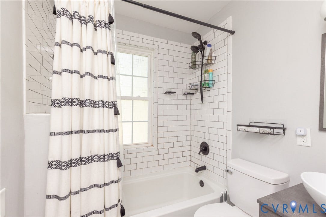 716 E Gladstone Avenue, Richmond, VA 23222 Bathtub with subway tile surround, matte black fixtures, and a white window
