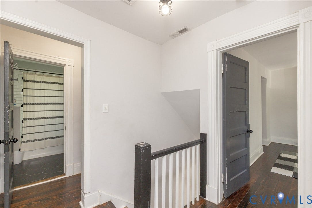 716 E Gladstone Avenue, Richmond, VA 23222 Dark wood-finish flooring, white wall paint, dark painted doors, and a decorative ceiling light fixture
