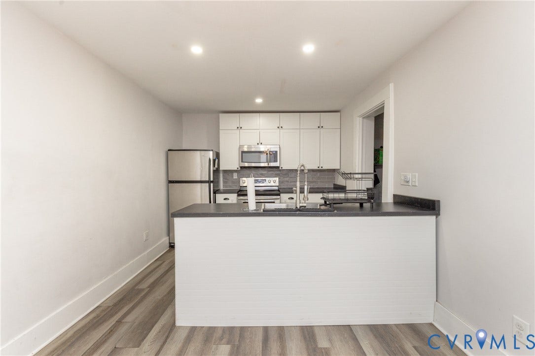 716 E Gladstone Avenue, Richmond, VA 23222 Kitchen featuring wood-finish flooring, recessed lighting, stainless steel appliances, white cabinetry, and dark countertops