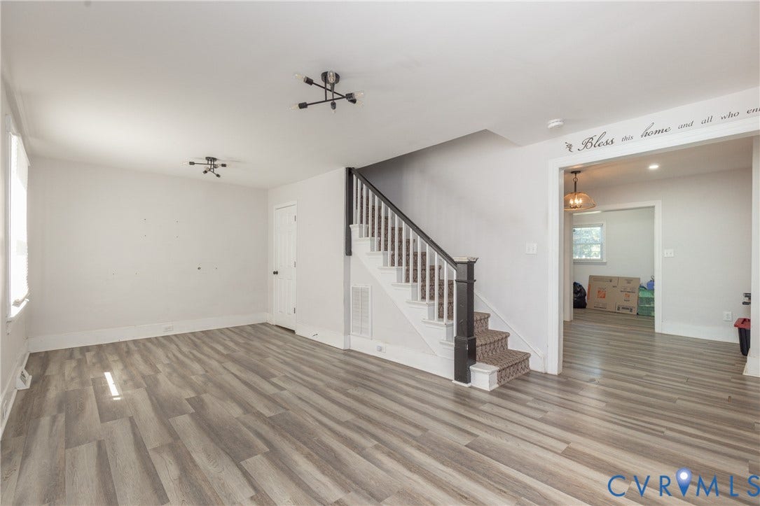 716 E Gladstone Avenue, Richmond, VA 23222 Wood-finish flooring, staircase with dark newel post and balusters, flush-mount lighting fixtures, and a cased opening