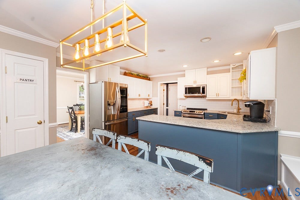 419 Rossmere Drive, Walton Park, Midlothian, VA 23114 Contemporary kitchen featuring a prominent island with a light-toned countertop, a gold-toned linear chandelier, stainless steel appliances, and a pantry door