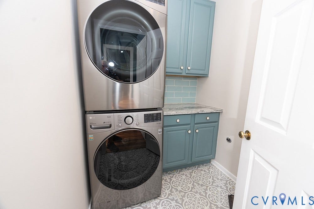 419 Rossmere Drive, Walton Park, Midlothian, VA 23114 Dedicated laundry area featuring stacked appliances, blue cabinetry, granite-style countertop, subway tile backsplash, and patterned flooring