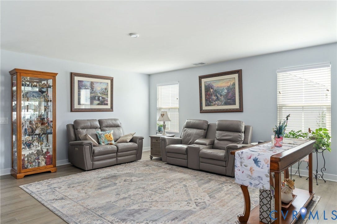 7484 Southamptonshire Way, Autumn Pines, New Kent, VA 23124 Spacious living area featuring light-toned walls, wood-finish flooring, and multiple windows with blinds