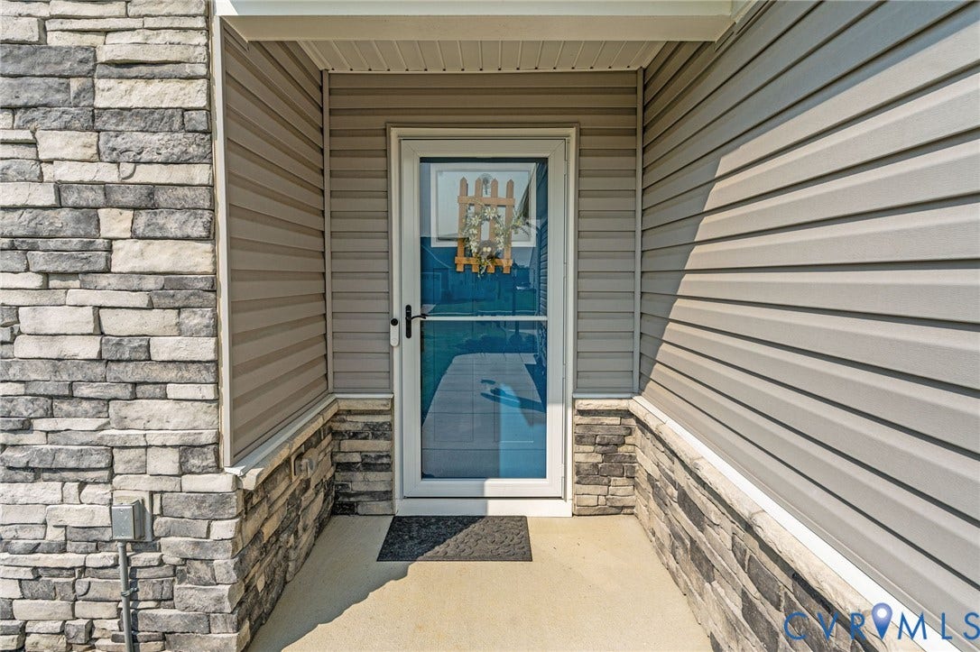 7484 Southamptonshire Way, Autumn Pines, New Kent, VA 23124 Front entry featuring a storm door, concrete porch, stacked stone facade, and horizontal siding
