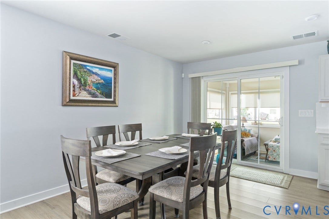 7484 Southamptonshire Way, Autumn Pines, New Kent, VA 23124 Dining area with wood-finish flooring, light grey wall paint, white trim, and a glass sliding door leading to an enclosed sunroom