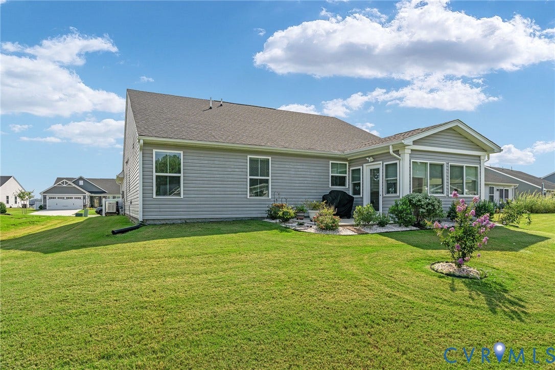 7484 Southamptonshire Way, Autumn Pines, New Kent, VA 23124 Expansive backyard with a manicured lawn, featuring a sunroom addition and a patio area
