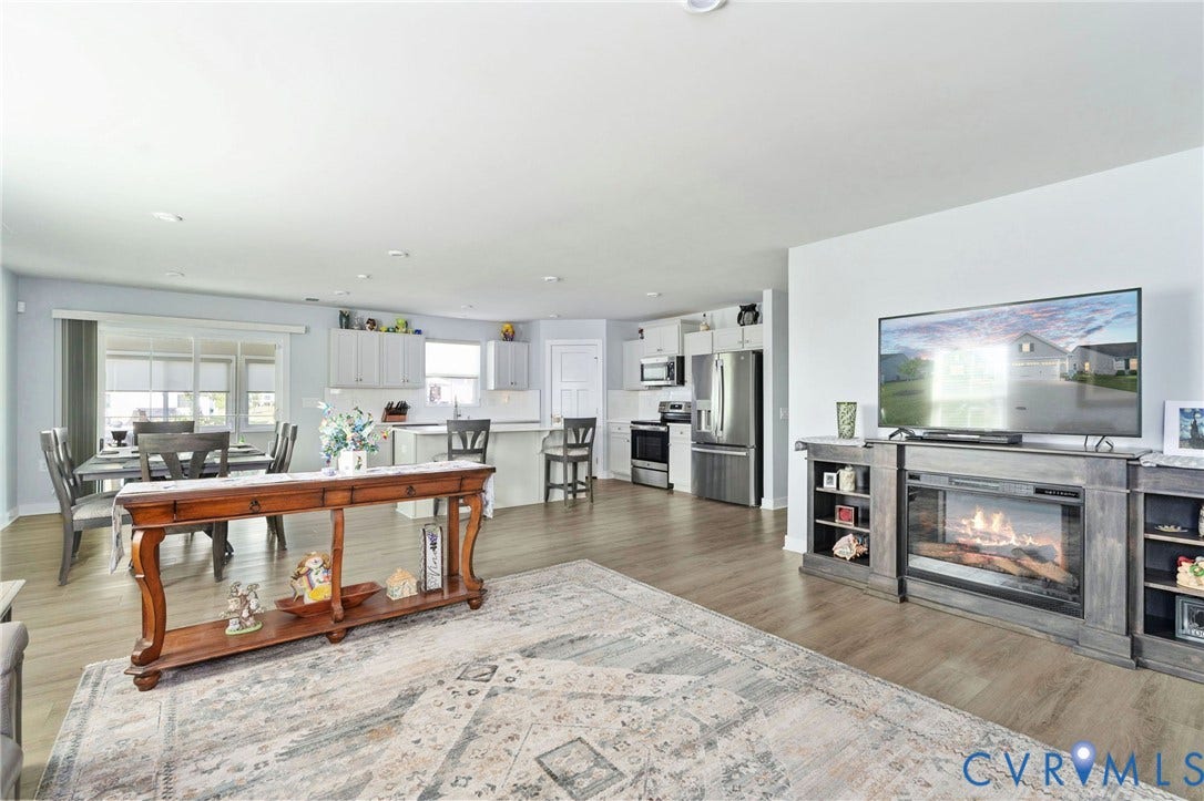 7484 Southamptonshire Way, Autumn Pines, New Kent, VA 23124 Open-concept living area featuring wood-finish flooring, recessed lighting, and a built-in electric fireplace entertainment center
