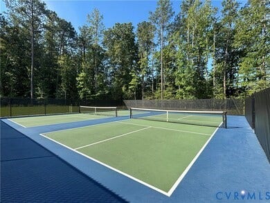 7484 Southamptonshire Way, Autumn Pines, New Kent, VA 23124 Dual-court athletic facility featuring a blue and green playing surface, black fencing, and perimeter tree line