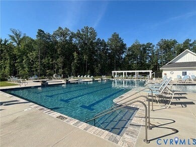 7484 Southamptonshire Way, Autumn Pines, New Kent, VA 23124 Outdoor swimming pool featuring integrated lap lanes, a surrounding concrete deck, and a pergola-covered patio area
