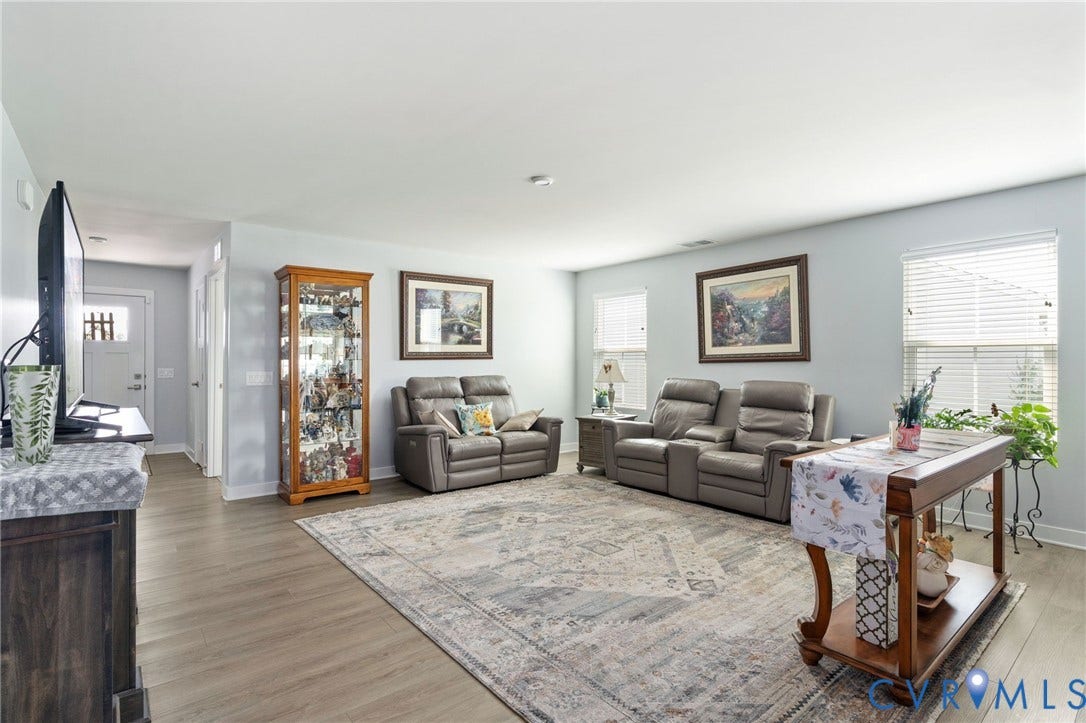 7484 Southamptonshire Way, Autumn Pines, New Kent, VA 23124 Spacious living area featuring light-toned wood-finish flooring, multiple windows with blinds, and recessed lighting