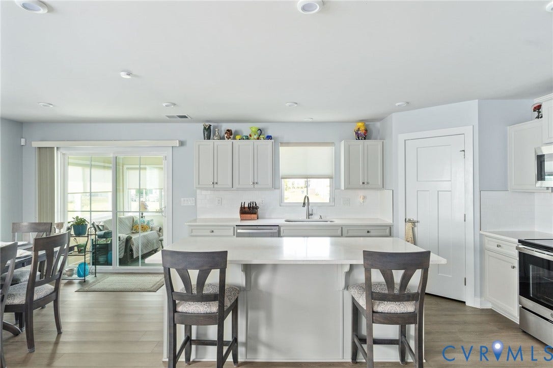 7484 Southamptonshire Way, Autumn Pines, New Kent, VA 23124 Kitchen featuring wood-finish flooring, recessed lighting, white shaker-style cabinetry, a central island with countertop seating, and a stainless steel sink with a pull-down faucet