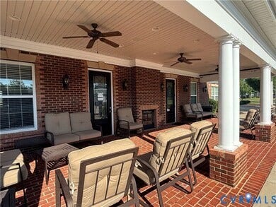 7484 Southamptonshire Way, Autumn Pines, New Kent, VA 23124 Expansive brick-paved patio featuring white columns, a beadboard ceiling with ceiling fans, and a built-in fireplace