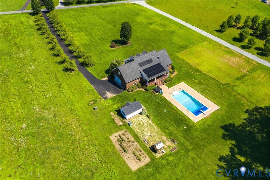 16225 Parrish Farms Road, Montpelier, VA 23192 Expansive property featuring a brick residence with solar panels, a rectangular swimming pool with diving board, a separate outbuilding, a cultivated garden area, and a paved driveway lined with trees