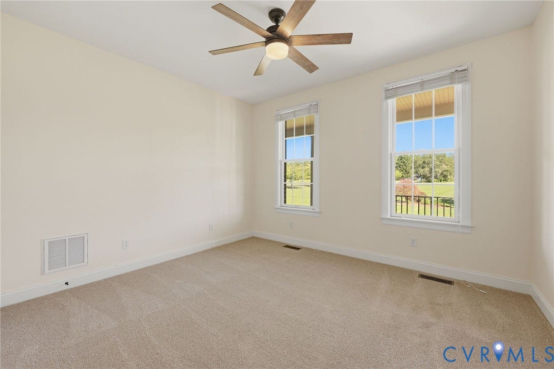 16225 Parrish Farms Road, Montpelier, VA 23192 First Floor guest bedroom Light-filled room featuring two windows with white trim, tan carpeting, a ceiling fan with wood-finish blades, and neutral-toned walls
