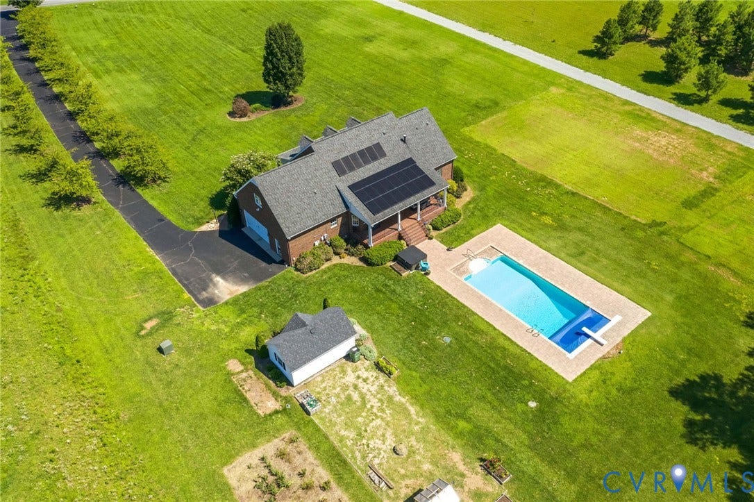 16225 Parrish Farms Road, Montpelier, VA 23192 Expansive property featuring a brick residence with solar panels, a rectangular swimming pool with paved surround, a detached outbuilding, and a long paved driveway bordered by mature trees