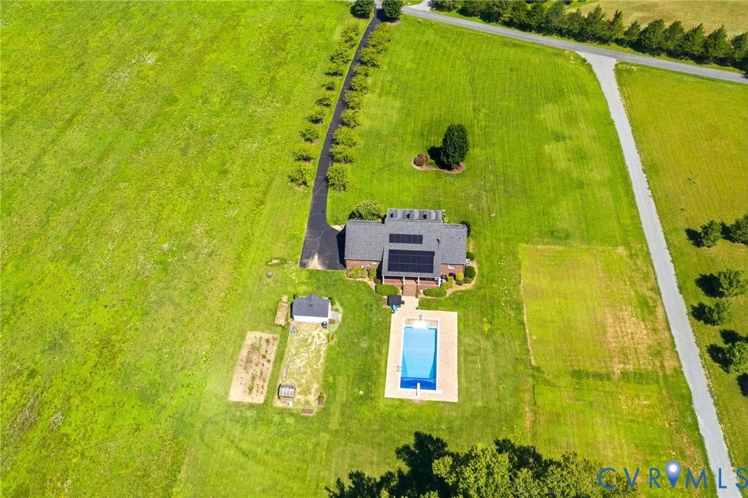 16225 Parrish Farms Road, Montpelier, VA 23192 Expansive property featuring a brick residence with a dark shingle roof, solar panels, and a rectangular swimming pool with surrounding deck