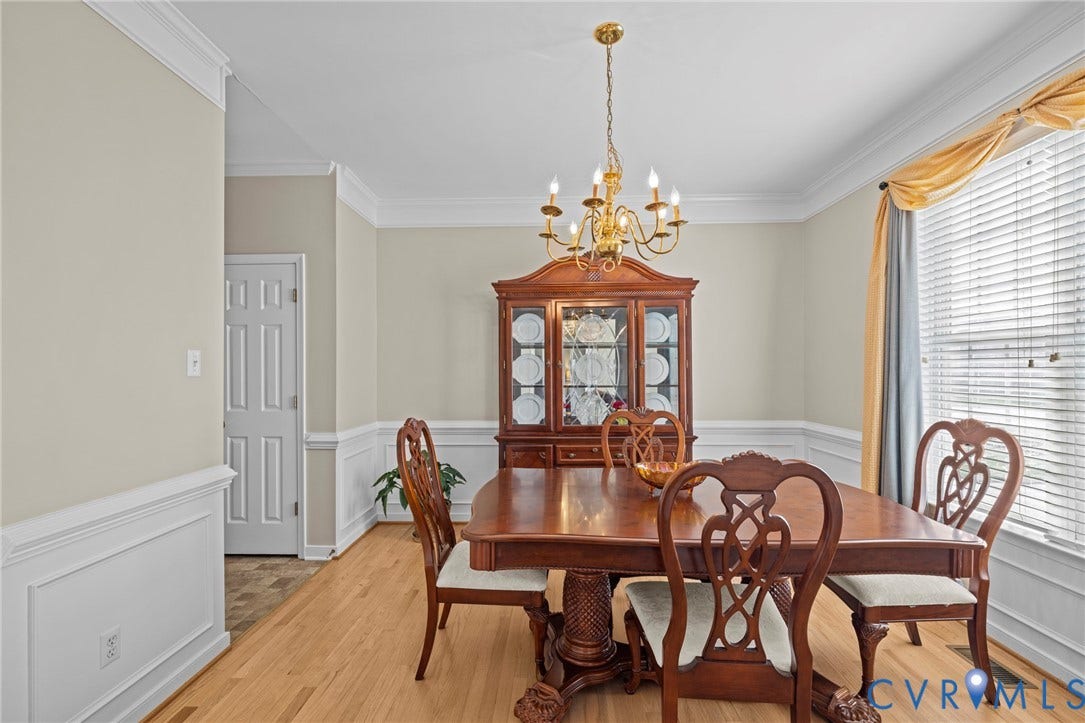 Formal dining area featuring hardwood flooring, crown molding, chair rail, and a chandelier