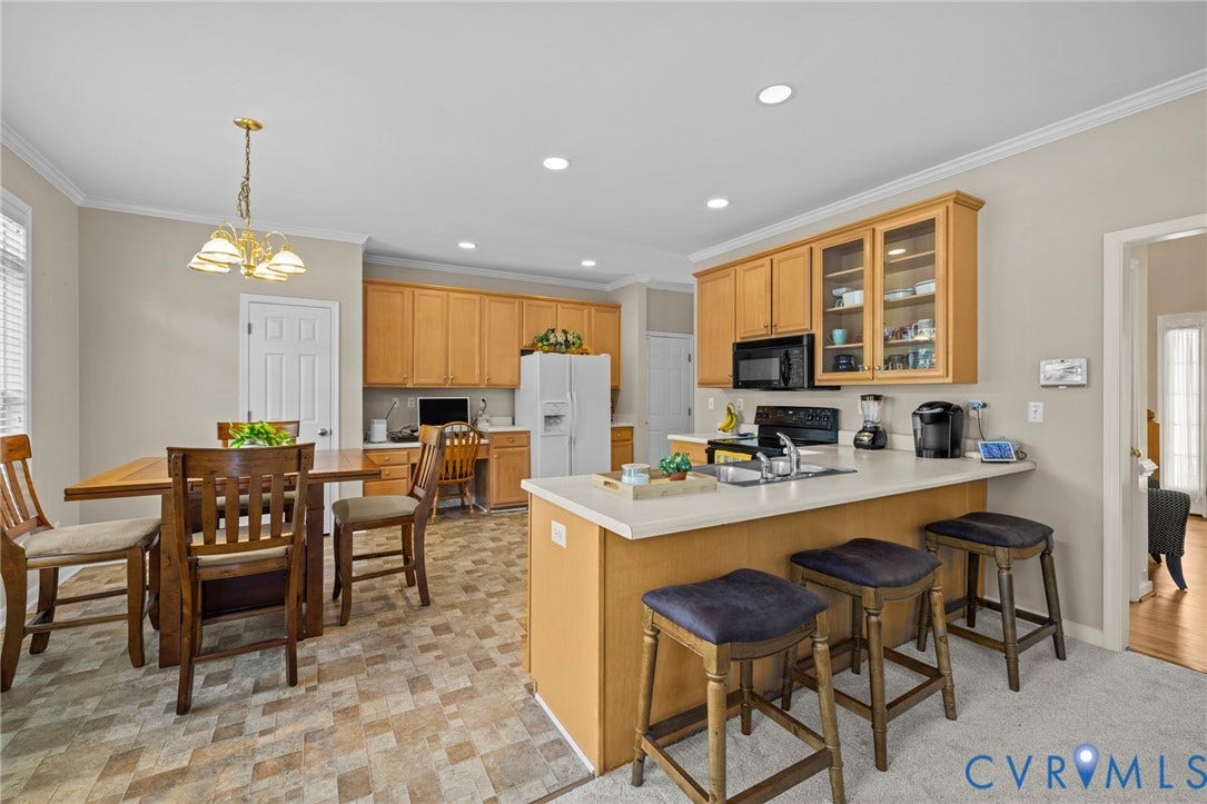 Open-concept kitchen with light wood cabinetry, a breakfast bar, and a built-in desk area