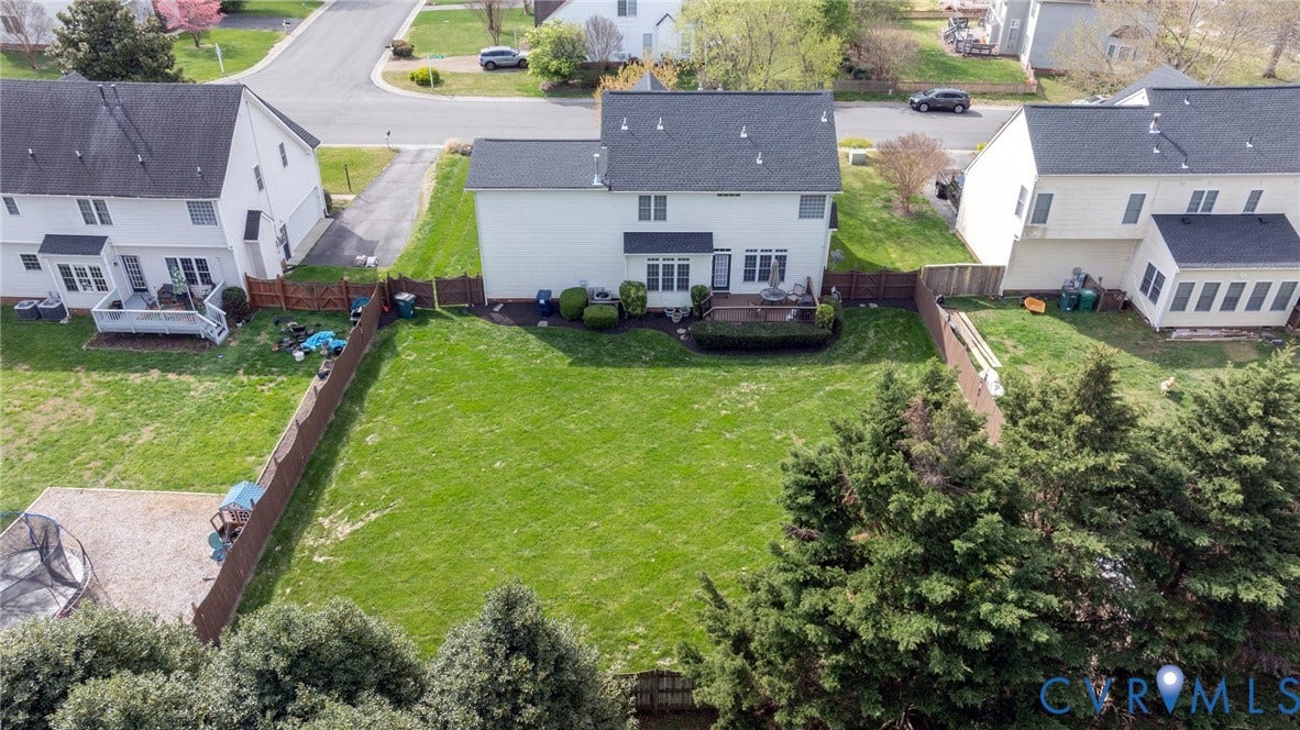 Expansive backyard featuring a manicured lawn, a multi-level wooden deck, and mature evergreen trees