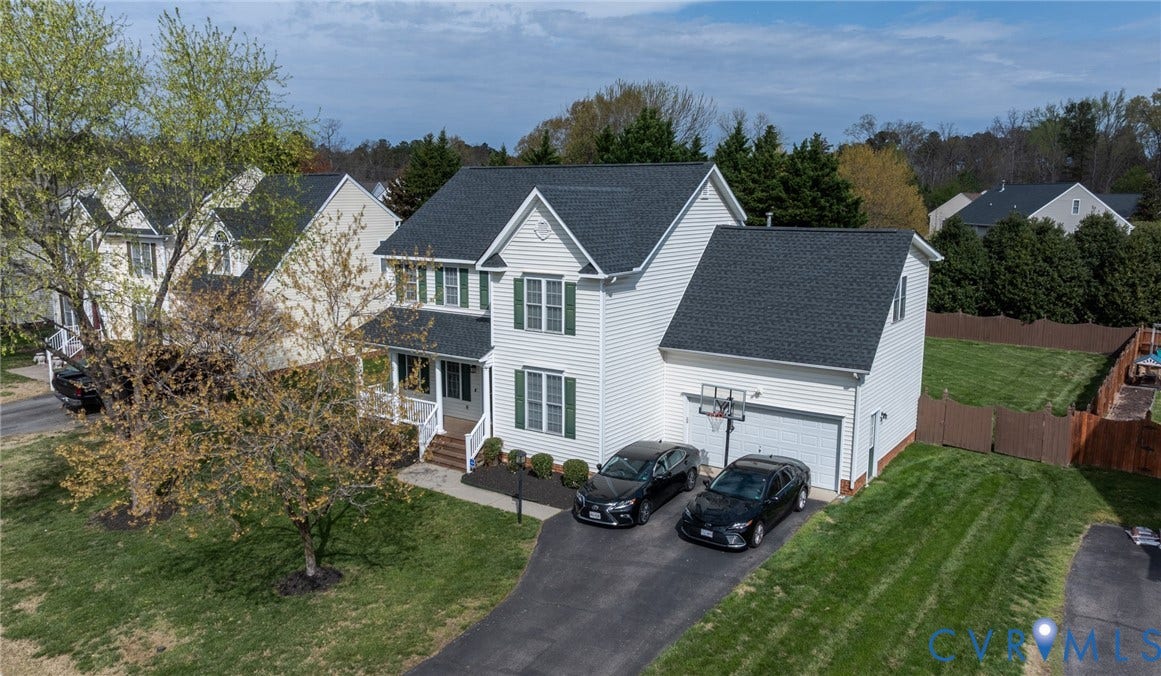 Two-story residence featuring white siding, dark shingle roofing, and green window shutters