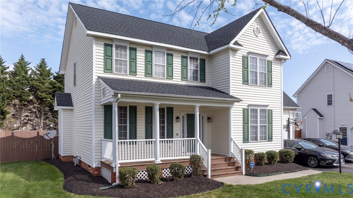 Two-story residence featuring light-colored siding and a dark shingle roof