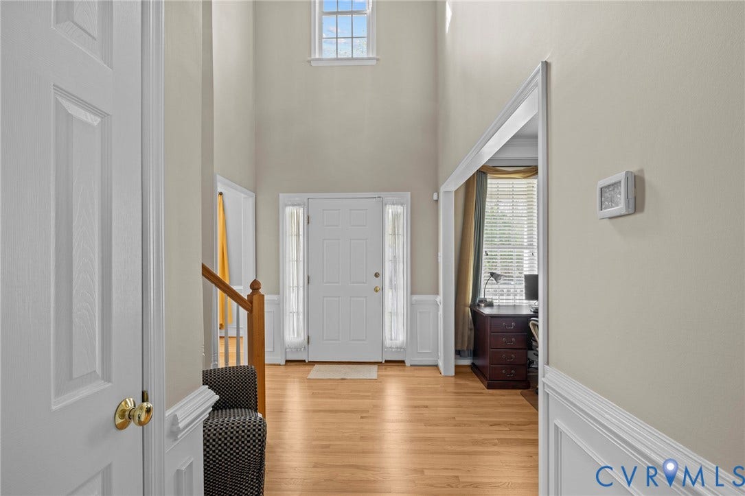 Two-story foyer with wood-finish flooring, wainscoting, and a prominent transom window