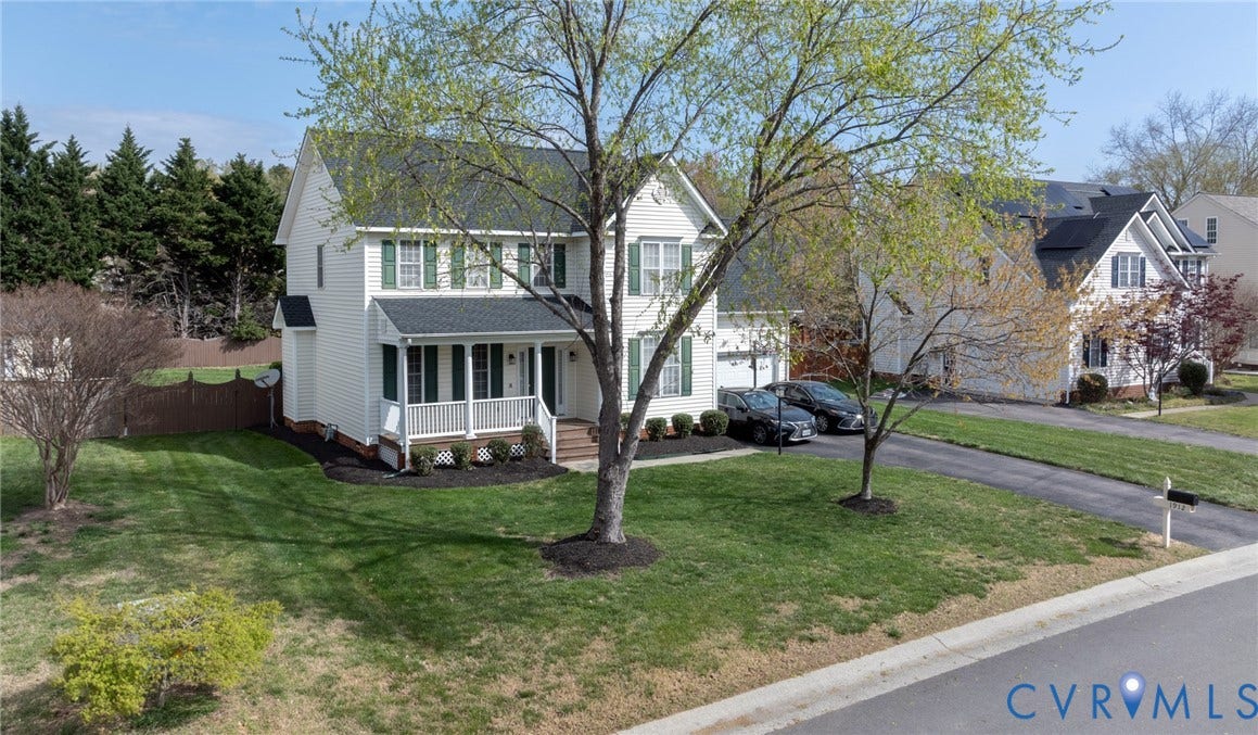Two-story residence featuring white siding and green shutters, a welcoming covered front porch, and a two-car garage