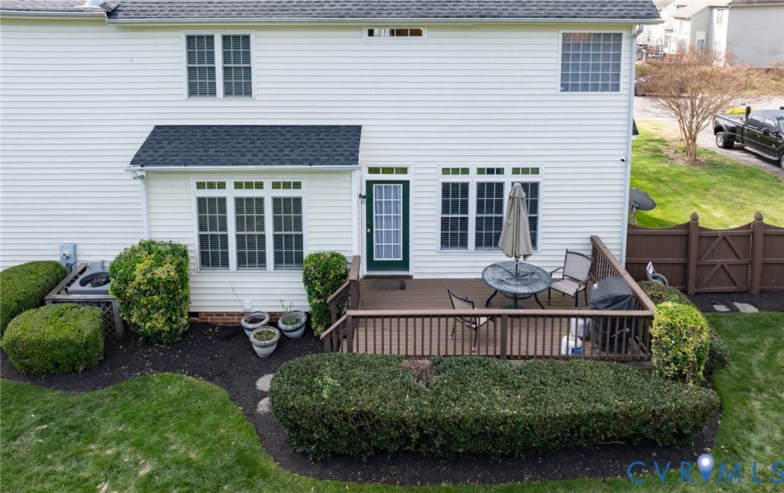 Rear exterior featuring a wood-finish deck with railing, white siding, and a dark shingle roof
